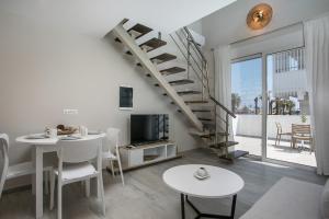 a living room with a staircase and a table and chairs at Avi Suites Faliraki in Faliraki