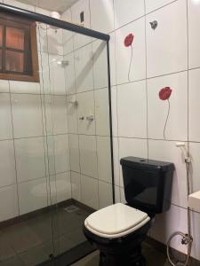 a bathroom with a toilet and a shower with red flowers on the wall at Bistrô Pousada Savacipó in Serra do Cipo +80 photos