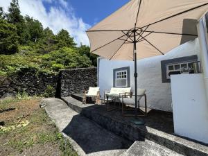 a table and chairs under an umbrella next to a house at Casa da Cisterna in São João