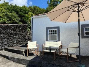 a patio with two chairs and an umbrella at Casa da Cisterna in São João +16 photos