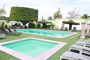 a swimming pool in a yard with lounge chairs at Posada de la Aldea in San Miguel de Allende