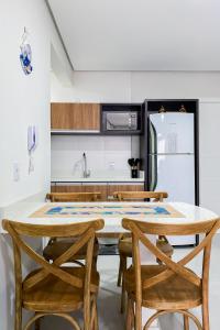 a kitchen with a table and chairs and a refrigerator at Apartamento super completo a 250mts do mar in Governador Celso Ramos