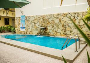 una piscina con parete in pietra e fontana di Hotel Las Palmeras a Piura