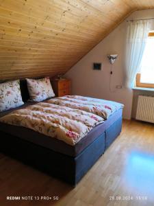 a bed in a room with a wooden ceiling at Ferienwohnung Altmühlblick in Pappenheim