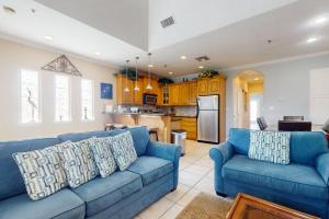 a living room with a blue couch and a kitchen at Garden Breeze Condominiums #3 in South Padre Island