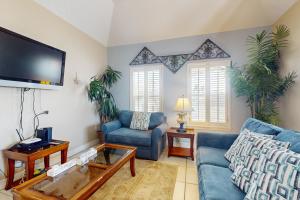 a living room with blue couches and a flat screen tv at Garden Breeze Condominiums #3 in South Padre Island