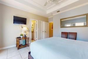 a bedroom with a white bed and a flat screen tv at Garden Breeze Condominiums #3 in South Padre Island +18 photos