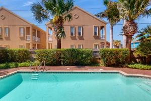 a swimming pool in front of a building with palm trees at Garden Breeze Condominiums #3 in South Padre Island