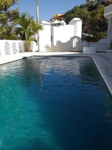 a swimming pool with blue water in front of a house at Manzanillo Breath Taking Views in Manzanillo