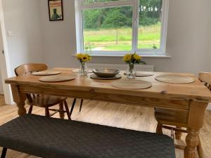 a wooden table with plates and flowers on top of it at Cheddar Head Bungalow in Rodney Stoke