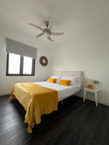 a white bedroom with a bed with a yellow blanket at Vista Bahia in Arrecife