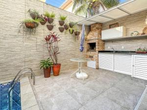 a patio with a table and potted plants on a wall at Piscina Privativa - Condominio - Churrasqueira - Espaçosa in Guarujá +36 photos