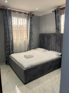a bed in a bedroom with a large window at La vue suites in Kampala