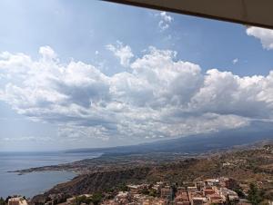 una vista su una città e sull'oceano sotto un cielo nuvoloso di Holiday Room "Pomelia 2" Taormina a Taormina Altre 6 foto