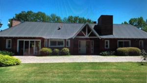 a brick house with a gambrel roof on a lawn at CONFORTABLE CASA EN HERMOSO y TRANQUILO CLUB DE CAMPO in Manzanares