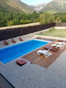 a swimming pool with a deck and chairs and a table and a pool at Halal Kuca sa bazenom u Mostaru in Mostar