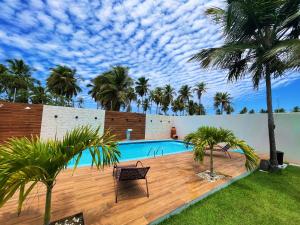 a swimming pool with palm trees in a backyard at Casa Quebec - Apartamentos in São Miguel do Gostoso