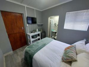 Un dormitorio con una gran cama blanca y un televisor. en Stay a While Self catering, en Newton Park