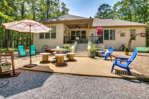 a house with a patio with chairs and an umbrella at Golf Course View Hot Springs Village Home! in Hot Springs Village