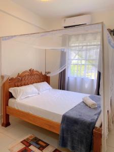 ein Schlafzimmer mit Himmelbett und Fenster in der Unterkunft Three Bedroom A2 Buxton Mombasa in Mombasa