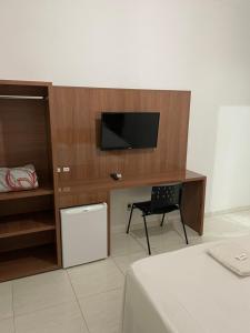 a room with a bed and a desk with a television at Hotel Prime in Hortolândia +4 photos