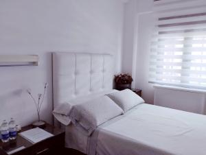 a white bedroom with a large white bed with a window at Habitaciones individuales en apartamento in Madrid
