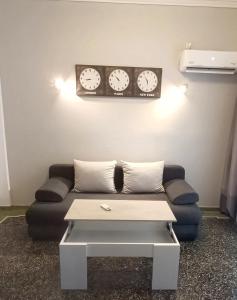 ein Wohnzimmer mit einem Sofa und Uhren an der Wand in der Unterkunft Thissio Hideaway Suite in Athen