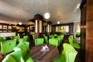 a restaurant with green chairs and a wooden table at Daily Plaza Boutique Hotel in Suceava