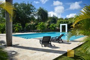 a swimming pool with two chairs and a table at 2JA Management Group - Condos White Hill in Sosúa