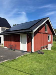 a red barn with a black roof on a yard at Louise guesthouse in Lindome +10 photos