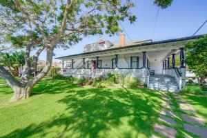 an old white house with a tree in the yard at Victorian Carpinteria Apartment Less Than 1 Mi to Beach! in Carpinteria