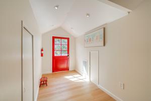 a red door in a white room with a wooden floor at Victorian Carpinteria Apartment Less Than 1 Mi to Beach! in Carpinteria