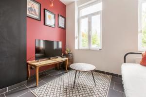 a living room with red walls and a tv at La Maison Jaurès - La Trappiste in Liévin