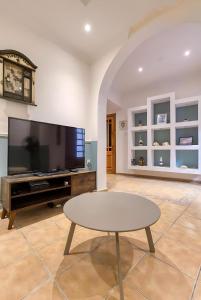 ein Wohnzimmer mit Flachbildfernseher und Tisch in der Unterkunft Ta' Lorita - Charming & Cosy Ground Floor Family Home in Vittoriosa