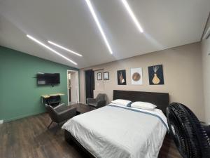 a bedroom with a bed and chairs and a television at Hospedaje cerca a centro comercial de Santafé A104 By Roots Rentals in Medellín