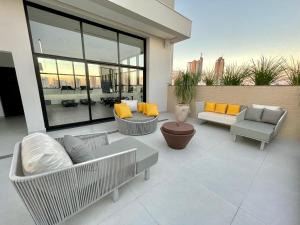 eine Terrasse mit Sofas und Stühlen auf einem Gebäude in der Unterkunft Luxury Collection Cama Queen e Sofá Cama Separado in Campo Grande