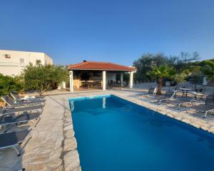 a swimming pool with chairs and a house at Murter Palms Resort Apartments in Murter
