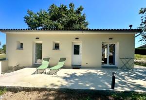 a group of chairs in front of a house at Maison neuve, cadre apaisant,jacuzzi et piscine in Planioles