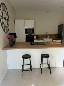 a kitchen with two bar stools and a large clock on the wall at Maison au bord de la Loire in Saint-Jean-le-Blanc
