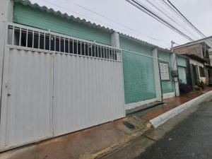 um edifício verde e branco com um portão em uma rua em Casa 2qts Vaga centro Arraial do cabo 5 min Praia em Arraial do Cabo