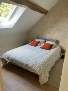 a bedroom with a bed with two red pillows at Maison au bord de la Loire in Saint-Jean-le-Blanc