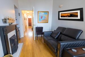 a living room with a black leather couch and a fireplace at Port Lush in Portrush