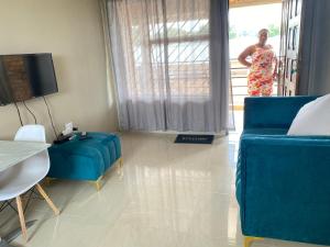 a woman standing in a living room with a blue couch at Kwadines Accommodation in Standerton