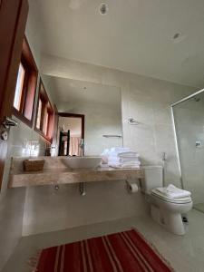 a bathroom with a sink and a toilet and a mirror at Casa Dois Mares in Pipa