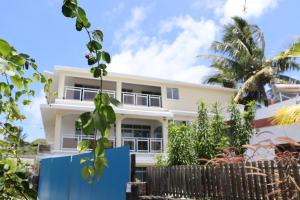 a white house with a fence in front of it at Family Luxurious Beach Penthouse in Trou d'Eau Douce