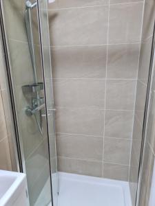 a shower with a glass door next to a sink at A memorable place in London, Plaistow in London