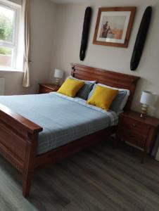 a bedroom with a wooden bed with yellow pillows at Donard Holidays in Newcastle
