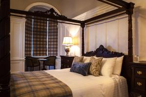 a bedroom with a canopy bed with a table and chairs at Inglewood House and Spa in Alloa