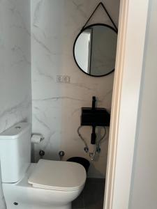 a bathroom with a white toilet and a mirror at CH Barco in Madrid