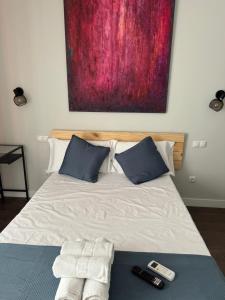 a bed with two remote controls and a painting on the wall at CH Barco in Madrid